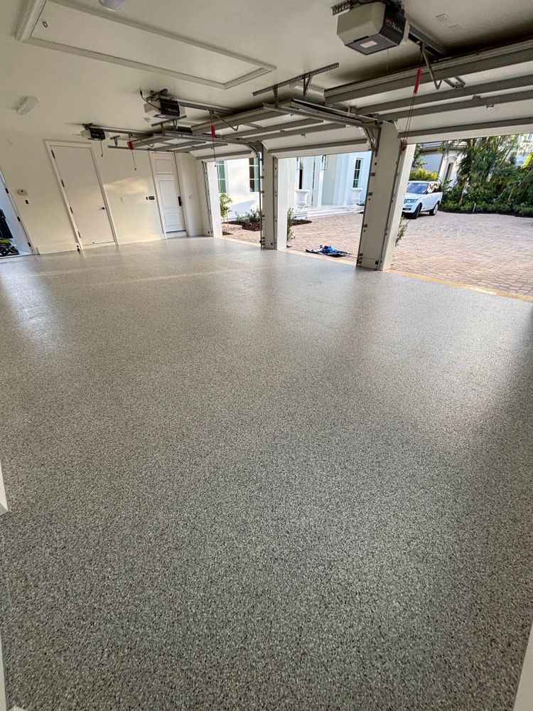 A garage with a concrete floor and a garage door open.