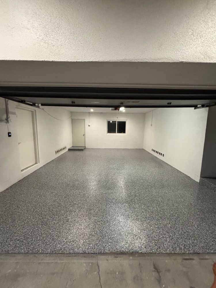 A large empty garage with a gray floor and white walls.