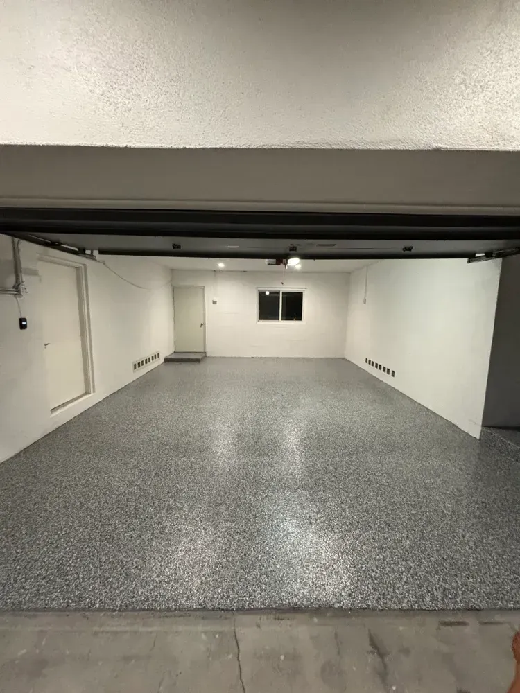 A large empty garage with a gray floor and white walls.
