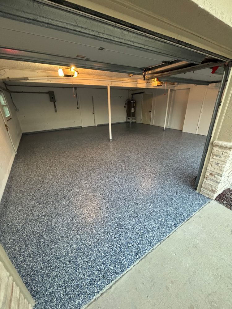 A garage with a concrete floor and a garage door open.