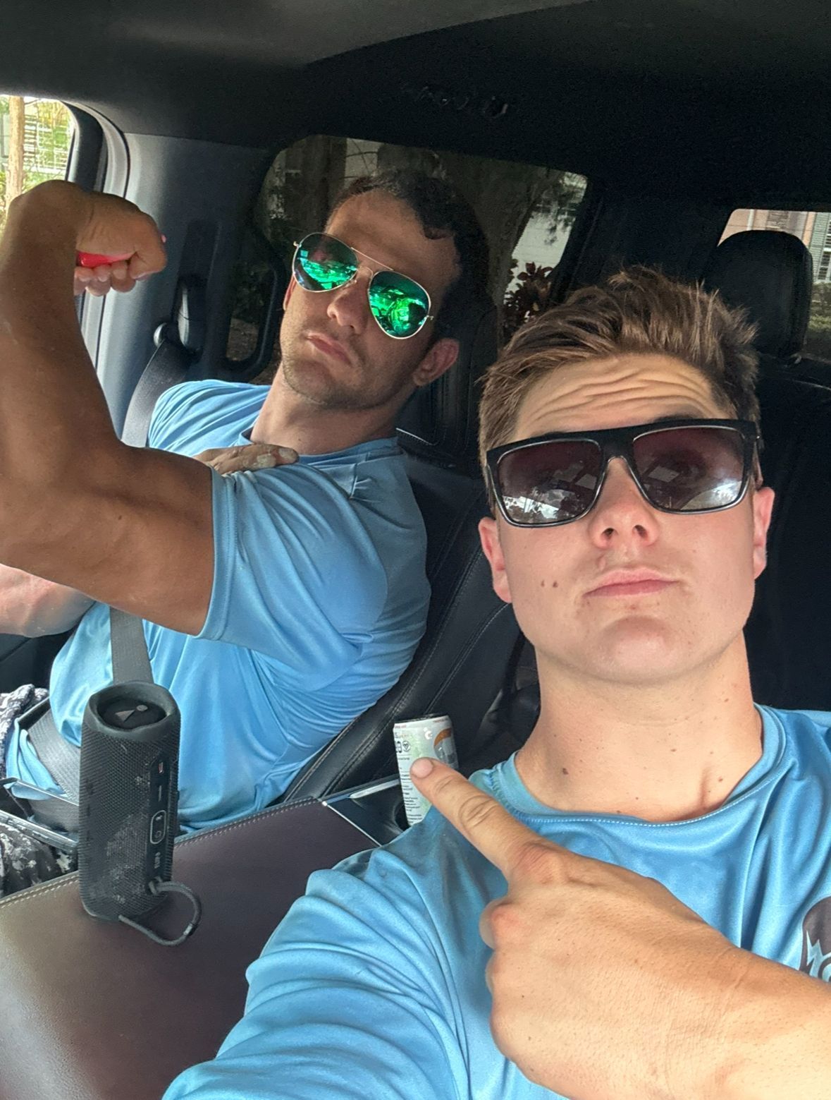 Two men wearing sunglasses are sitting in a car.