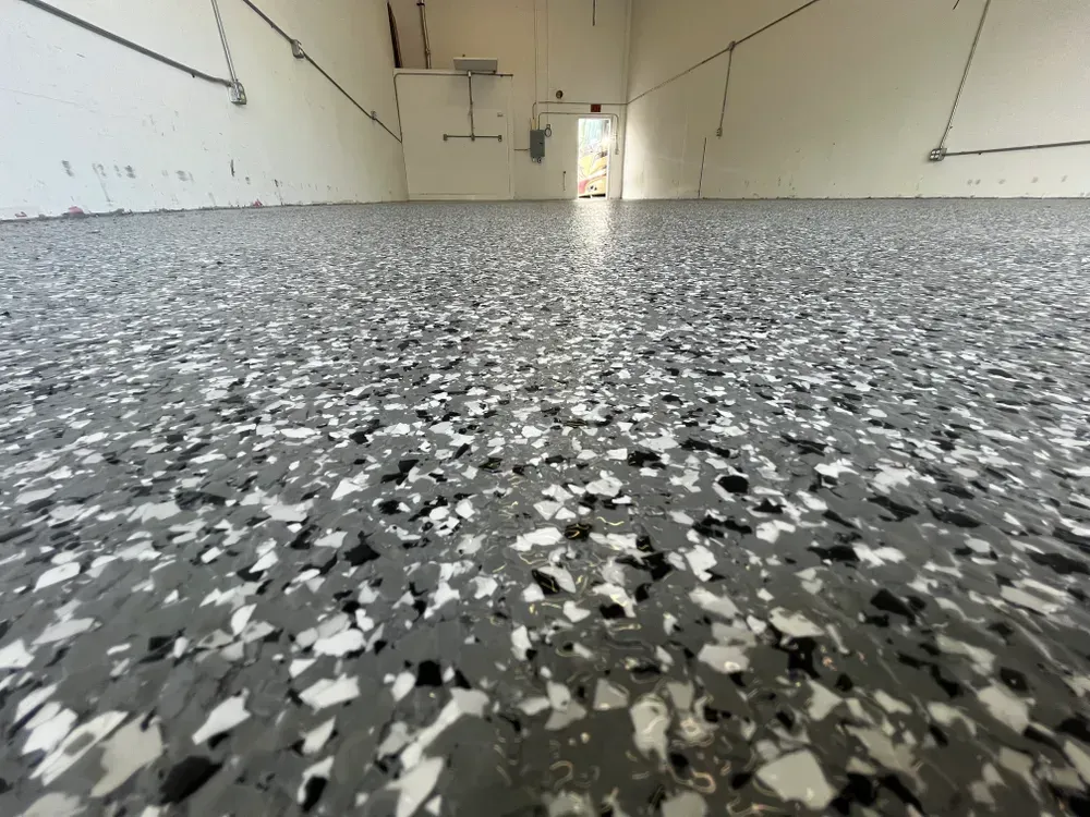 A garage floor with a lot of black and white flakes on it.