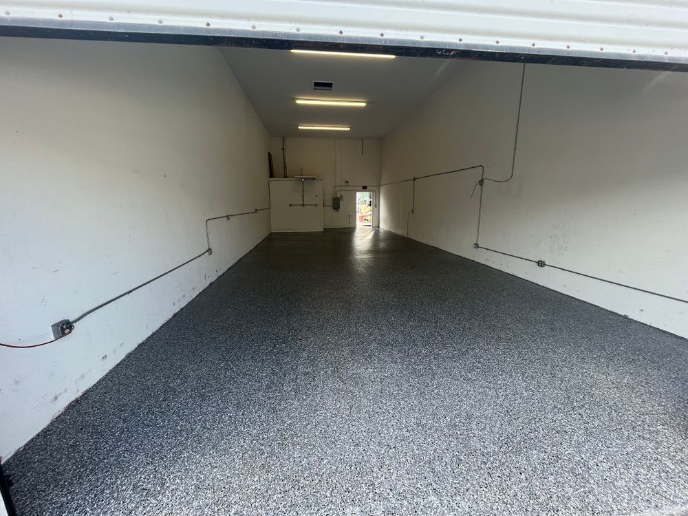 An empty garage with a gray floor and white walls