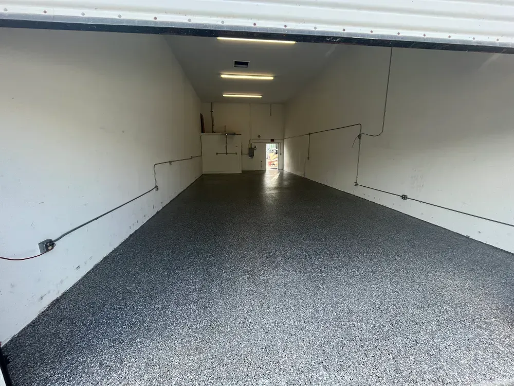 An empty garage with a gray floor and white walls
