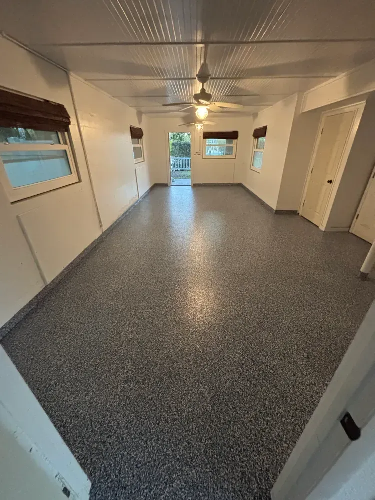 A large room with a ceiling fan and a gray floor.