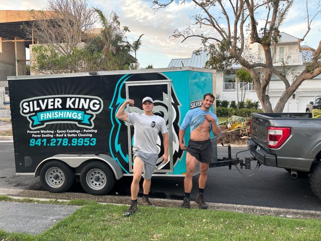 Two men are standing in front of a silver king trailer.