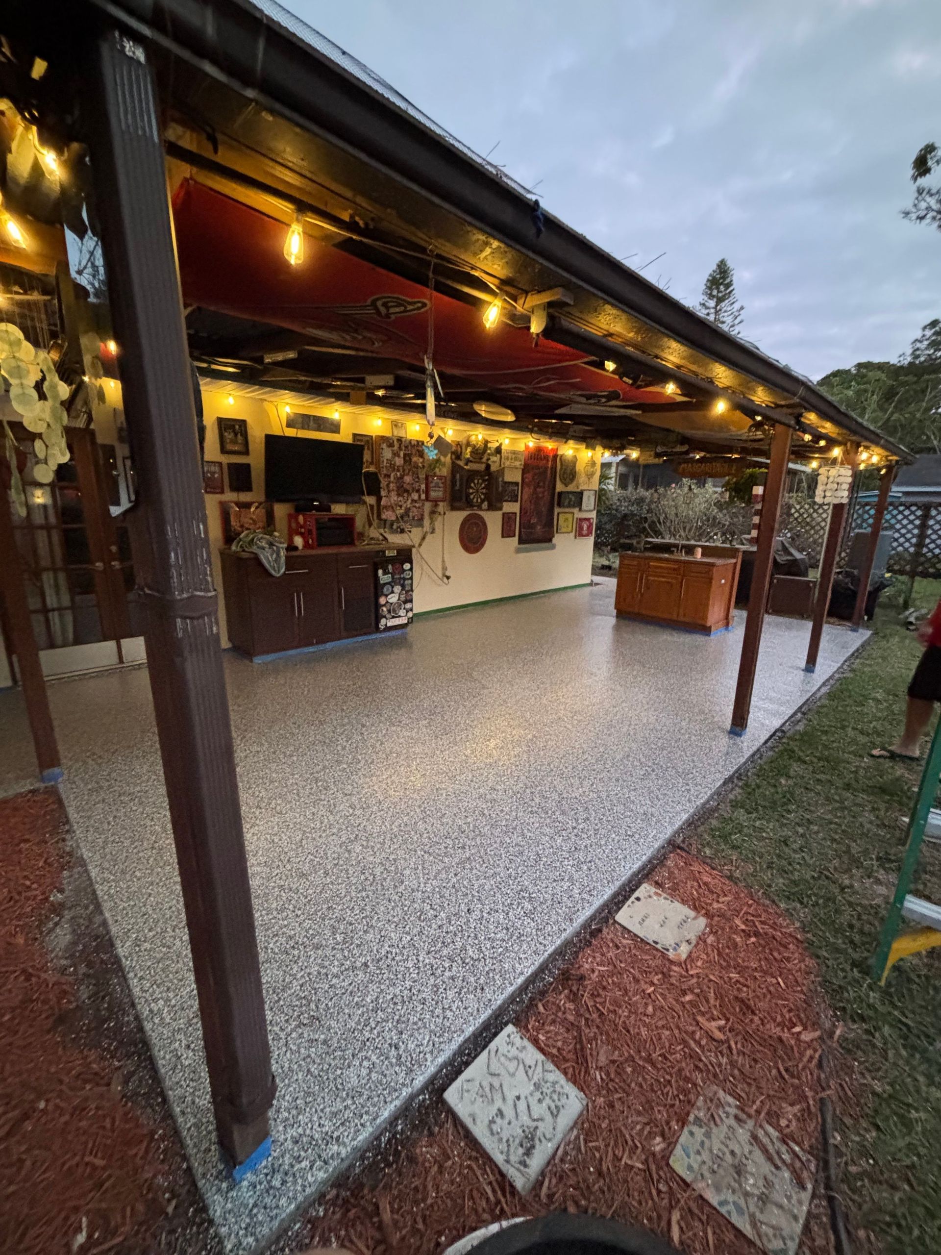 A patio with a covered roof and a concrete floor.