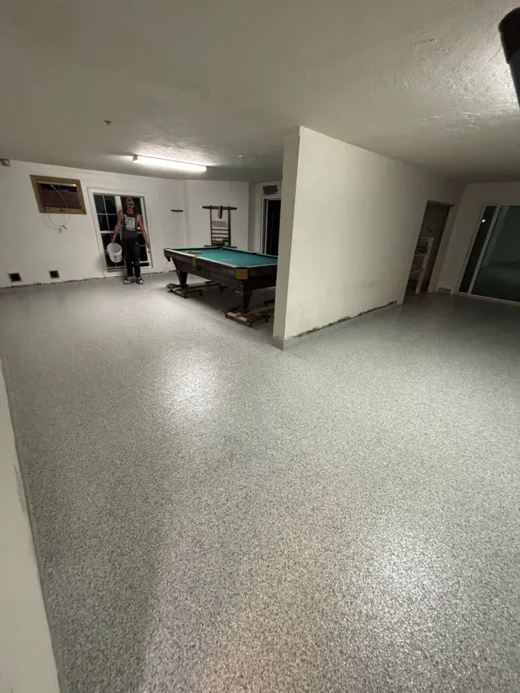 A man is standing in a room with a pool table.
