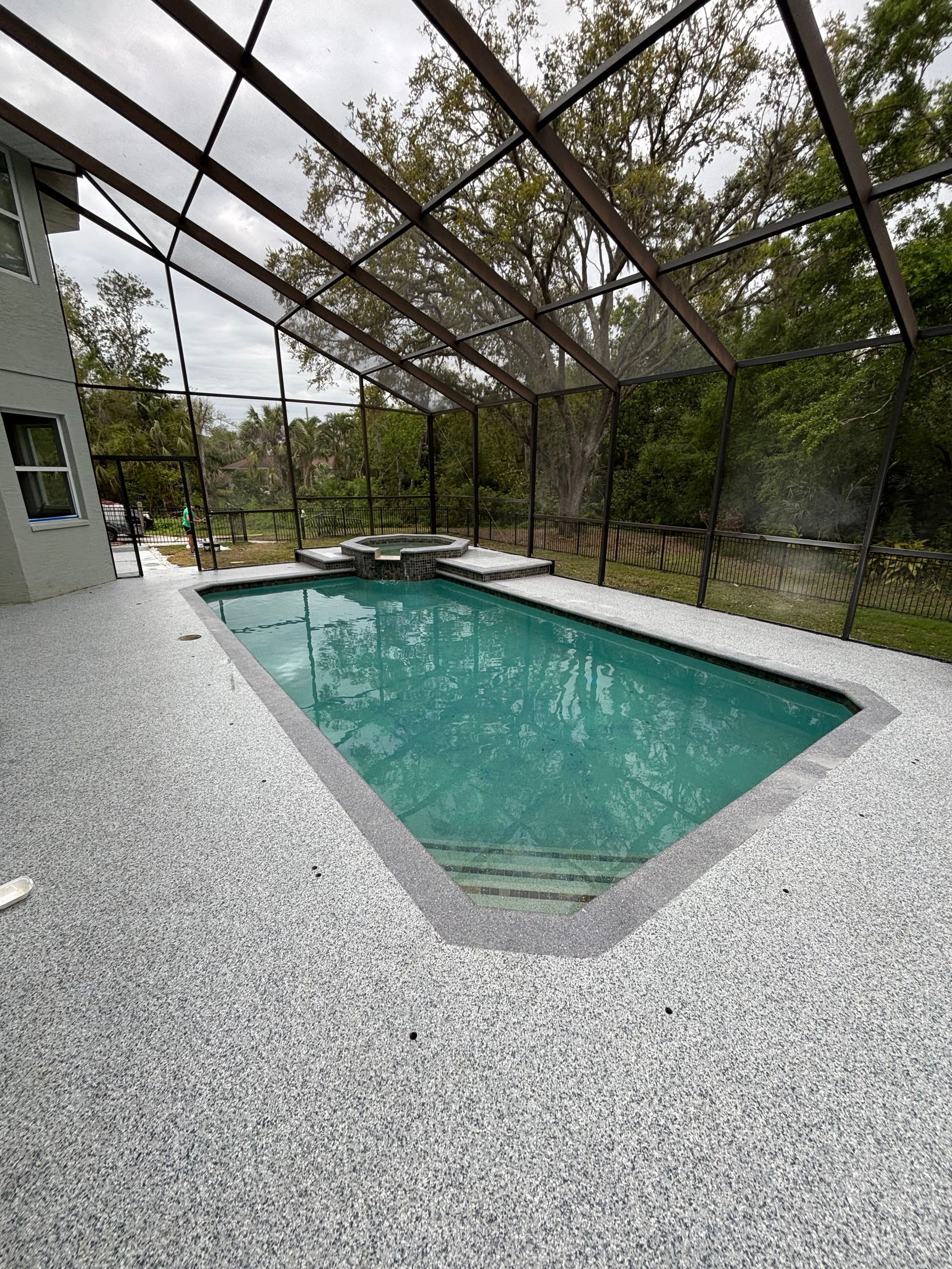 A large swimming pool with a screened in area in the backyard of a house.