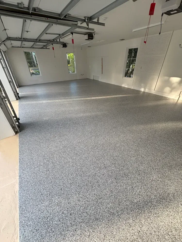 A large empty garage with a gray floor and white walls.