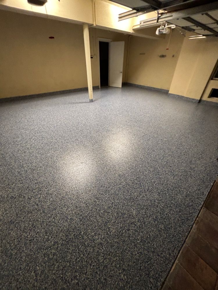 A large empty room with a gray floor and a door.