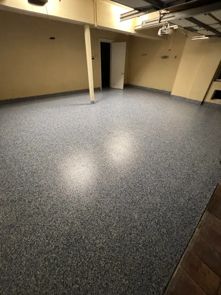 A large empty room with a gray floor and a door.