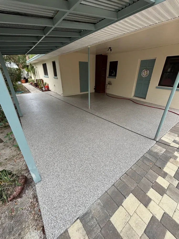 A covered walkway leading to a house with a concrete floor.