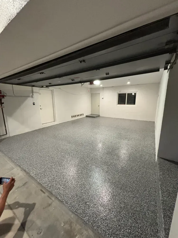 A garage with a garage door open and a gray floor.