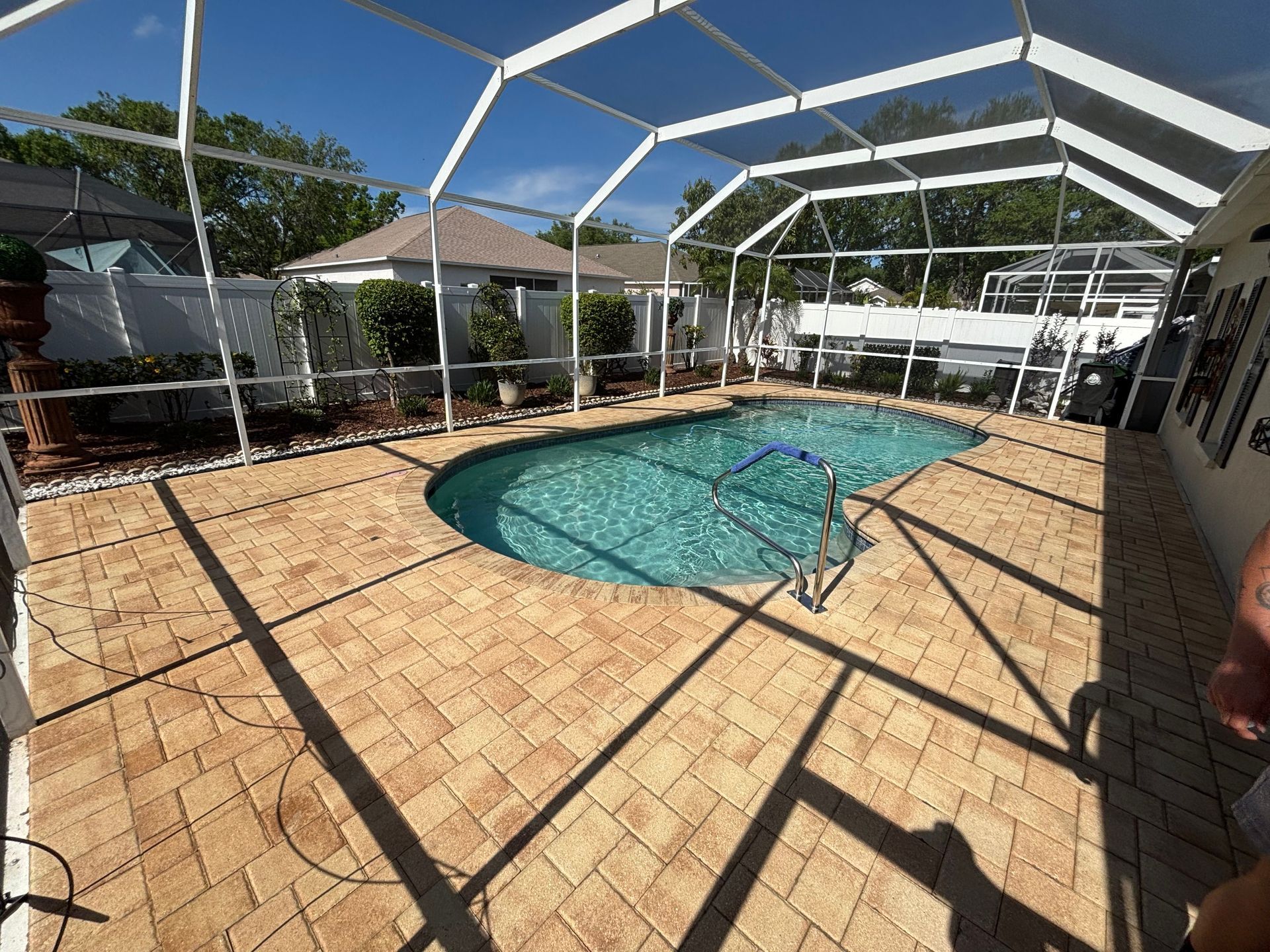 A large swimming pool is surrounded by a screened in area.