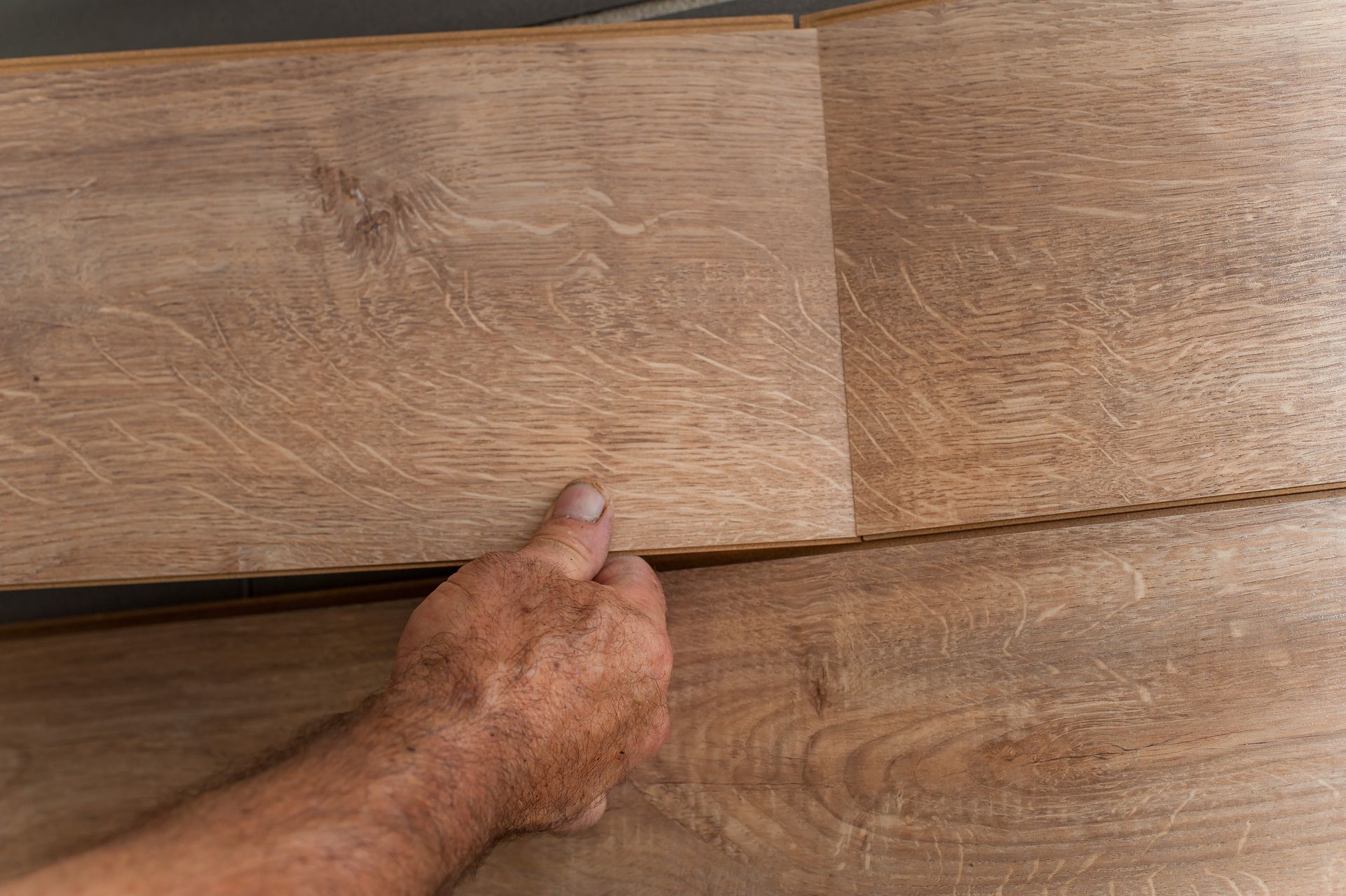 A man installing laminate flooring planks