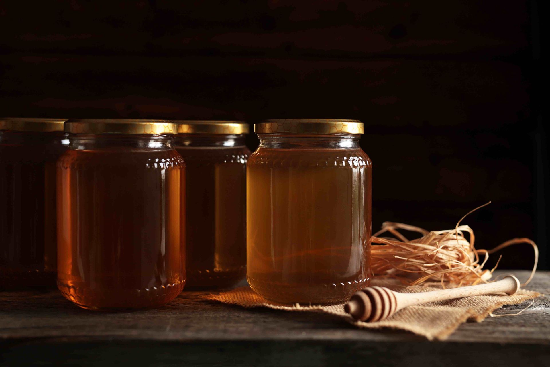 A picture of jars of honey on a wooden table to depict the honey and amber color of flooring