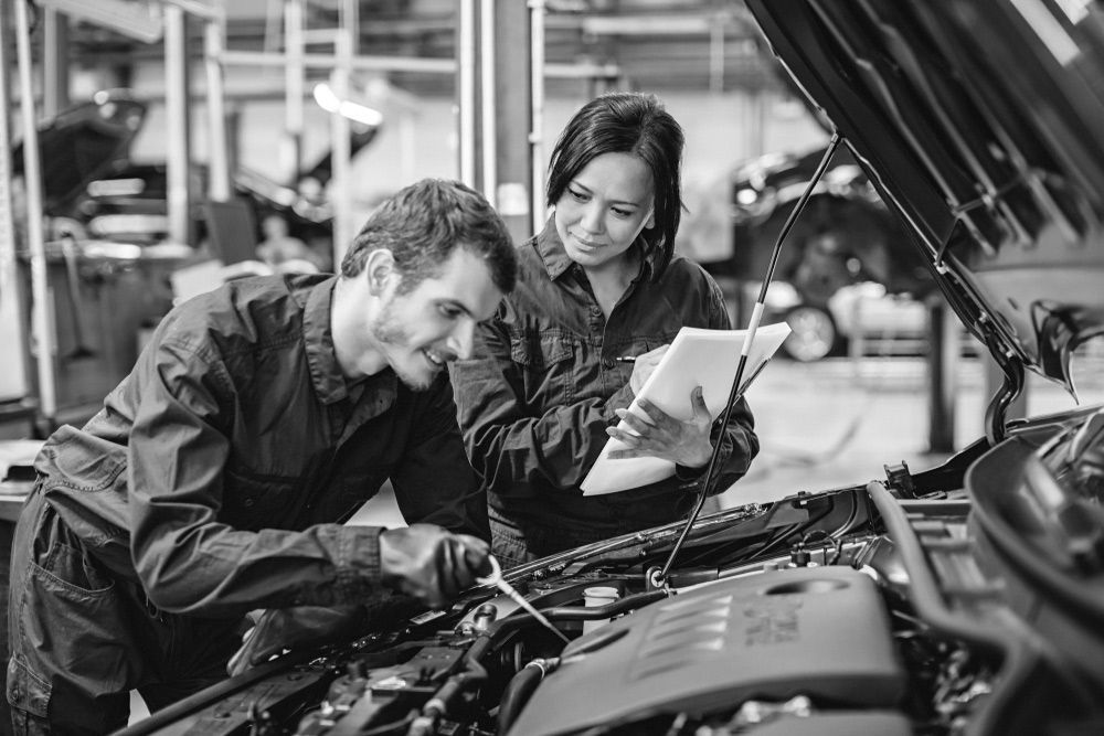 A Man And A Woman Are Working On A Car In A Garage — Advanced Auto Tech In Port Macquarie, NSW