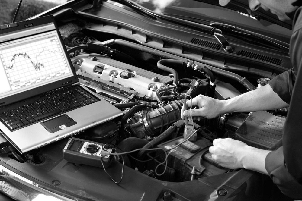 A Man Is Working On The Engine Of A Car With A Laptop — Advanced Auto Tech In Port Macquarie, NSW