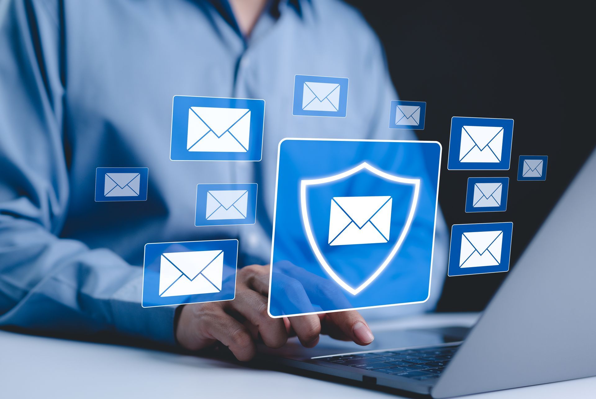 Person using laptop with floating email icons and a blue shield, suggesting online security or spam protection