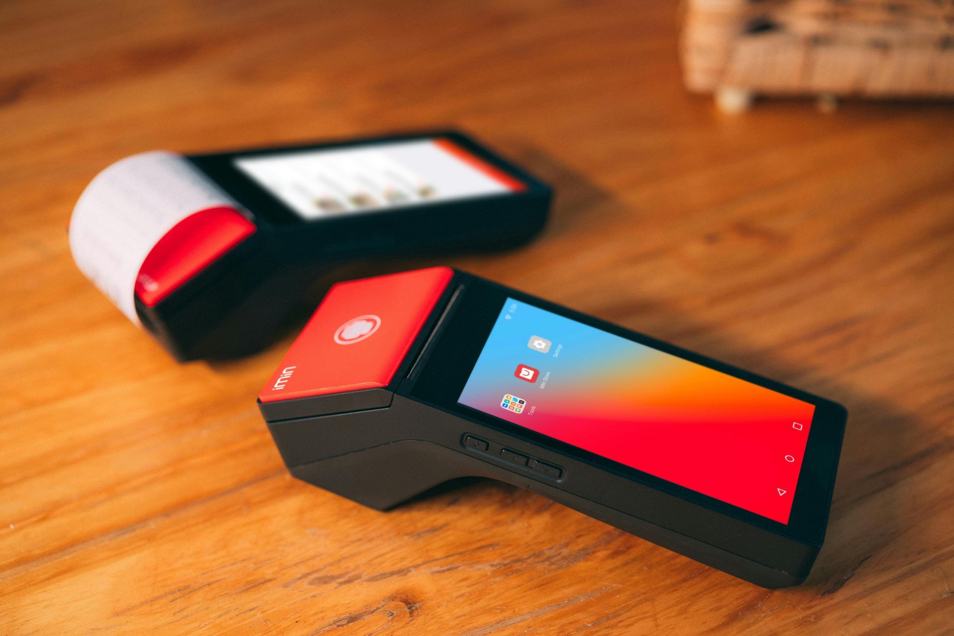 Two smart phones are sitting on a wooden table.