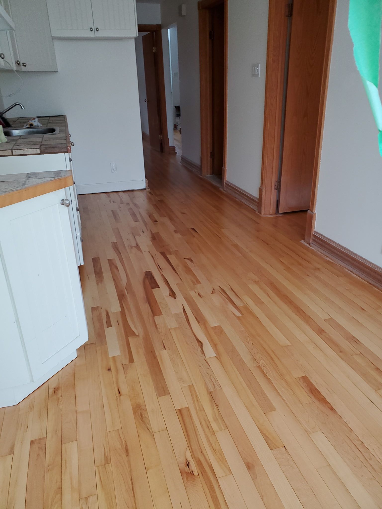 Une cuisine avec planchers de bois franc et armoires blanches.