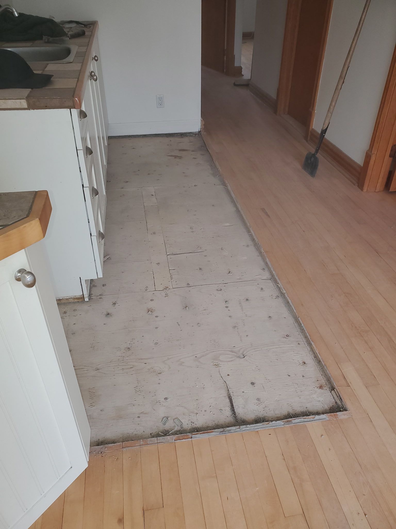 Une cuisine avec un plancher en bois et des armoires blanches