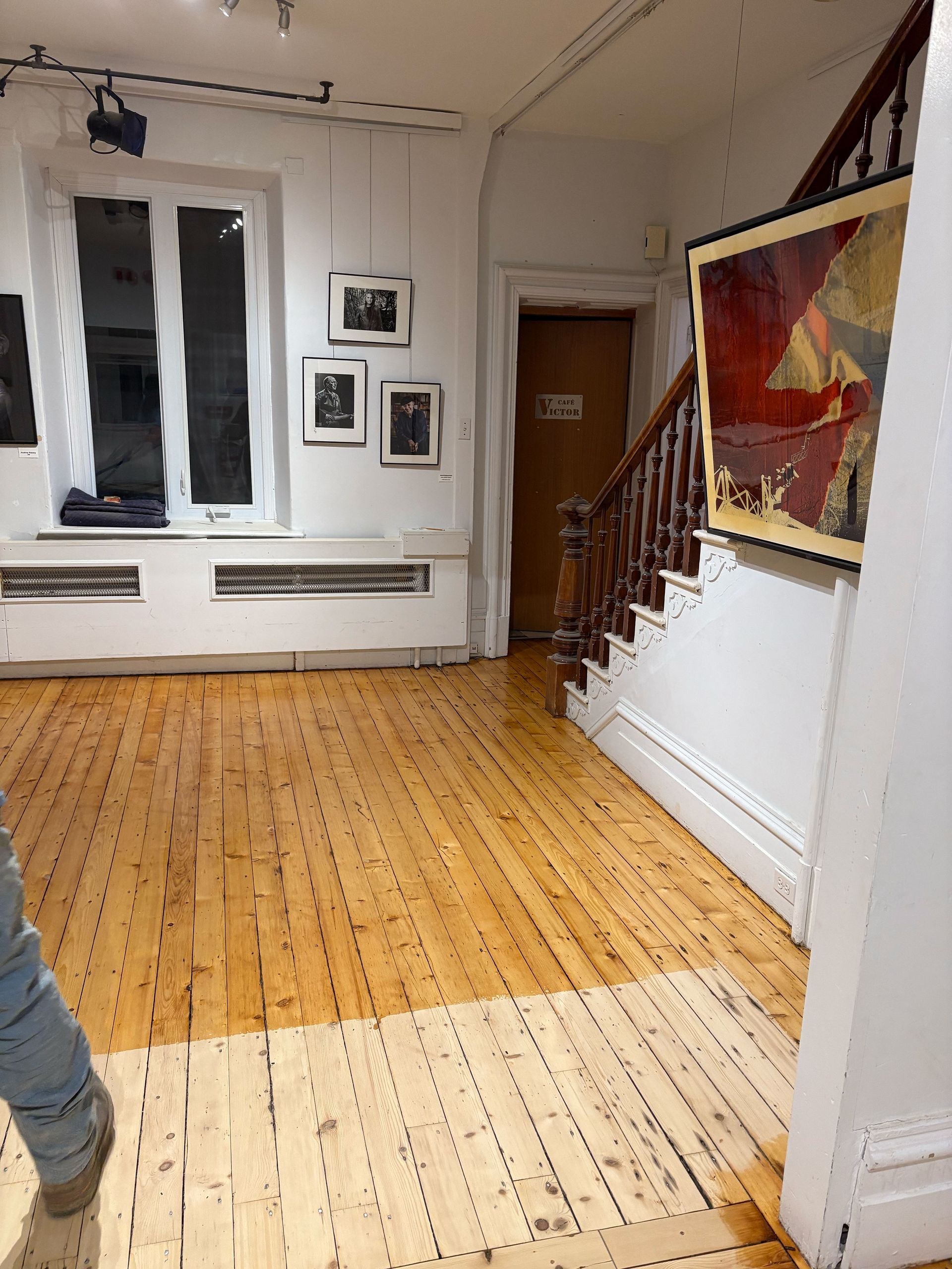 Une personne se tient dans un couloir avec un plancher en bois et des escaliers.