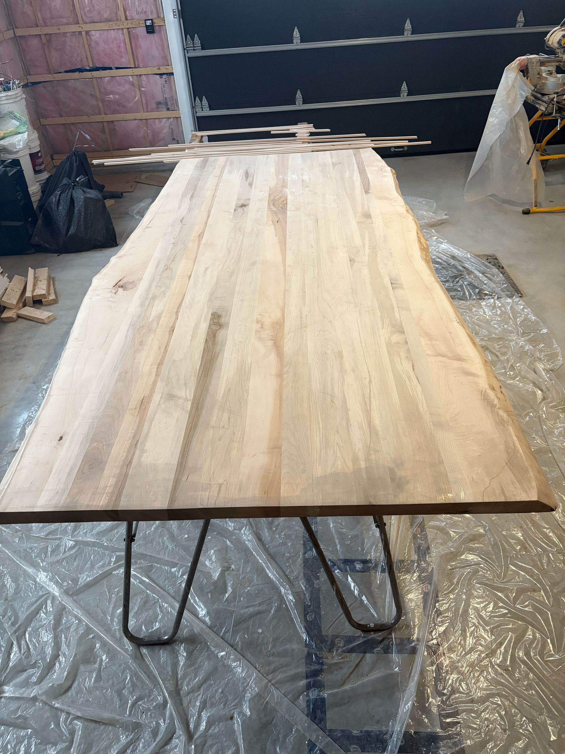 Une table en bois avec des pieds en épingle à cheveux est posée dans une pièce recouverte de plastique.