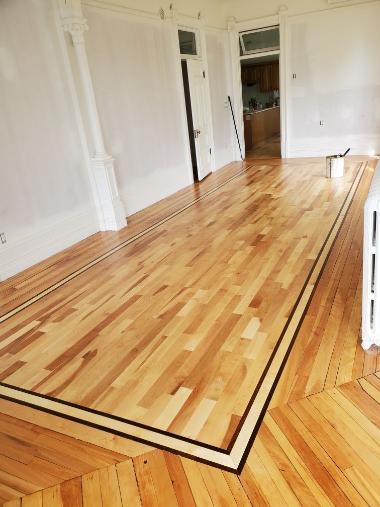 Une pièce avec un parquet et des murs blancs