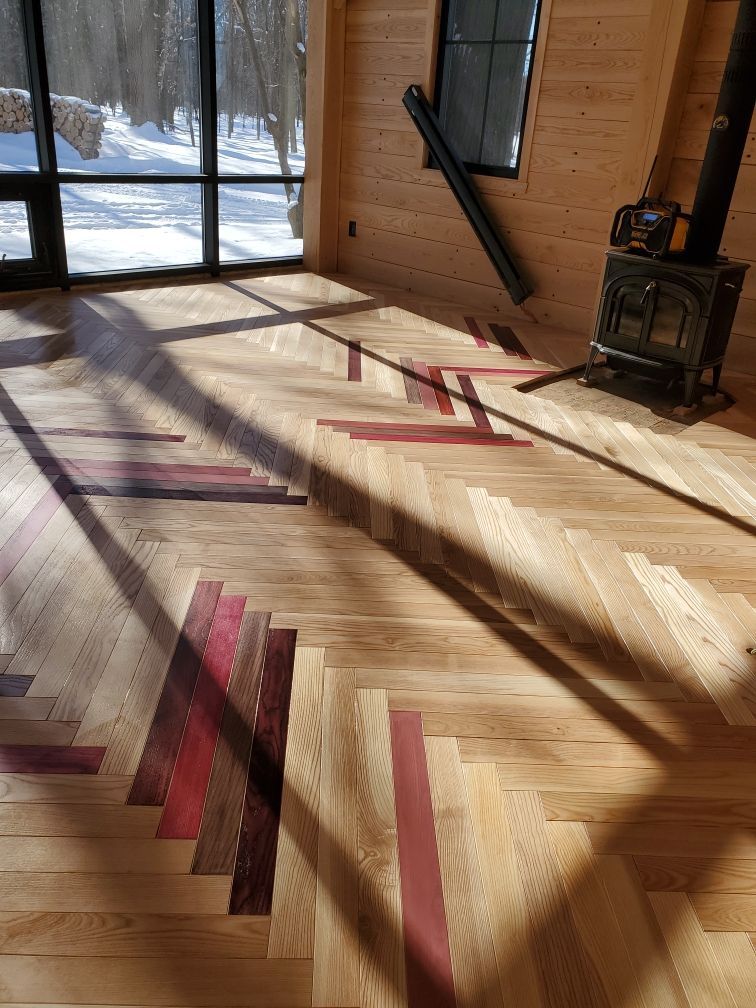 Un séjour avec un poêle à bois et un parquet en chevrons.