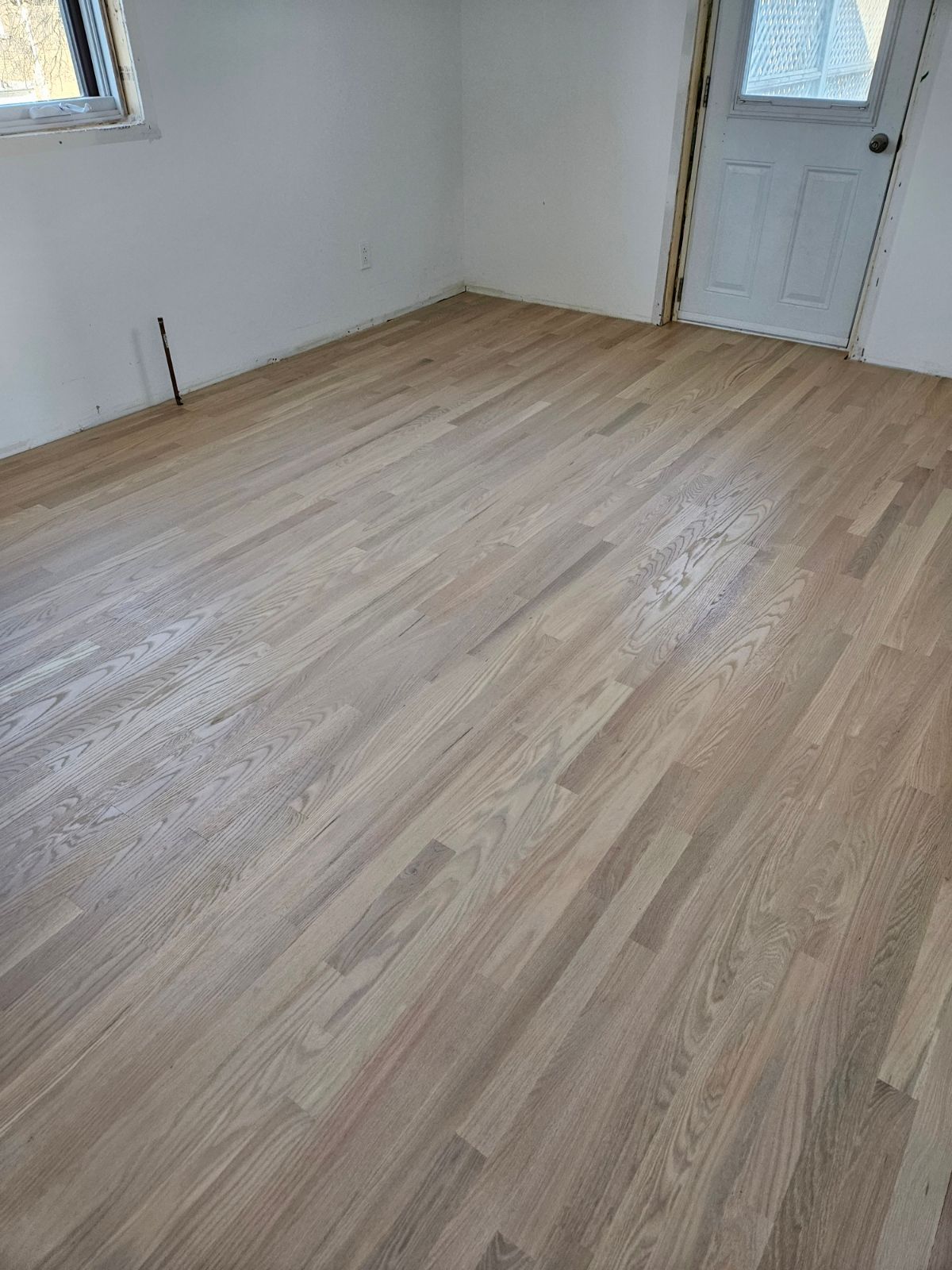 Une pièce avec un plancher en bois et une porte.