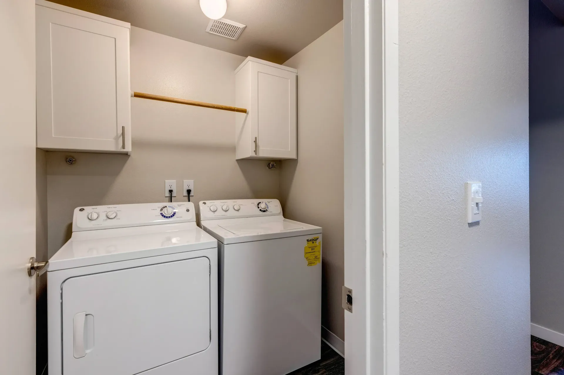 In-unit laundry closet with white front-load dryer and top-load washer, white cabinets above.