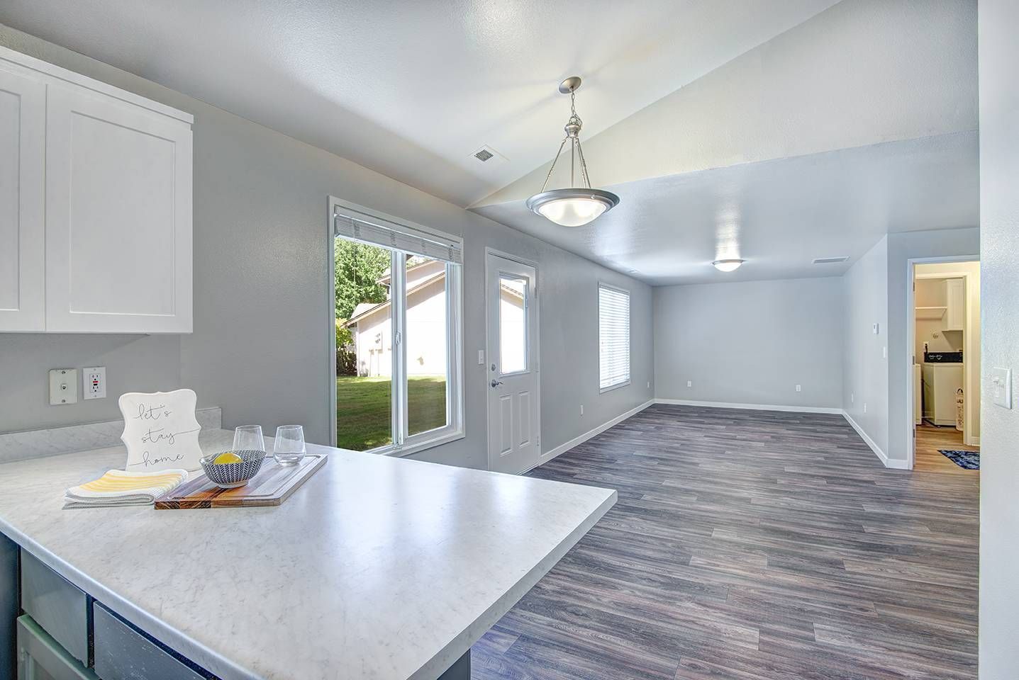 Open-concept kitchen and living area with a white island, gray walls, and a sliding glass door.