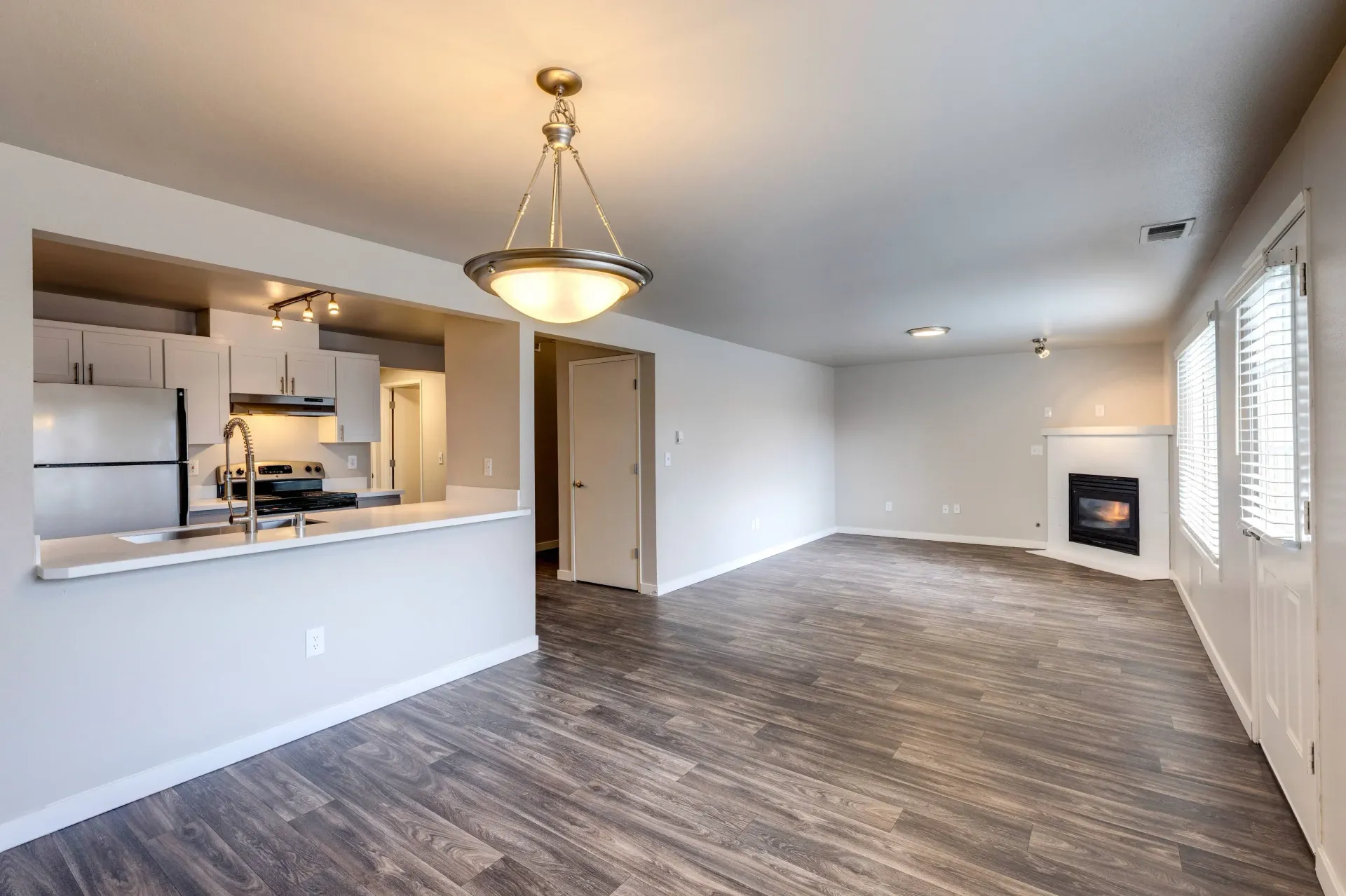 Open-concept living area with kitchen island, stainless appliances, and a fireplace.