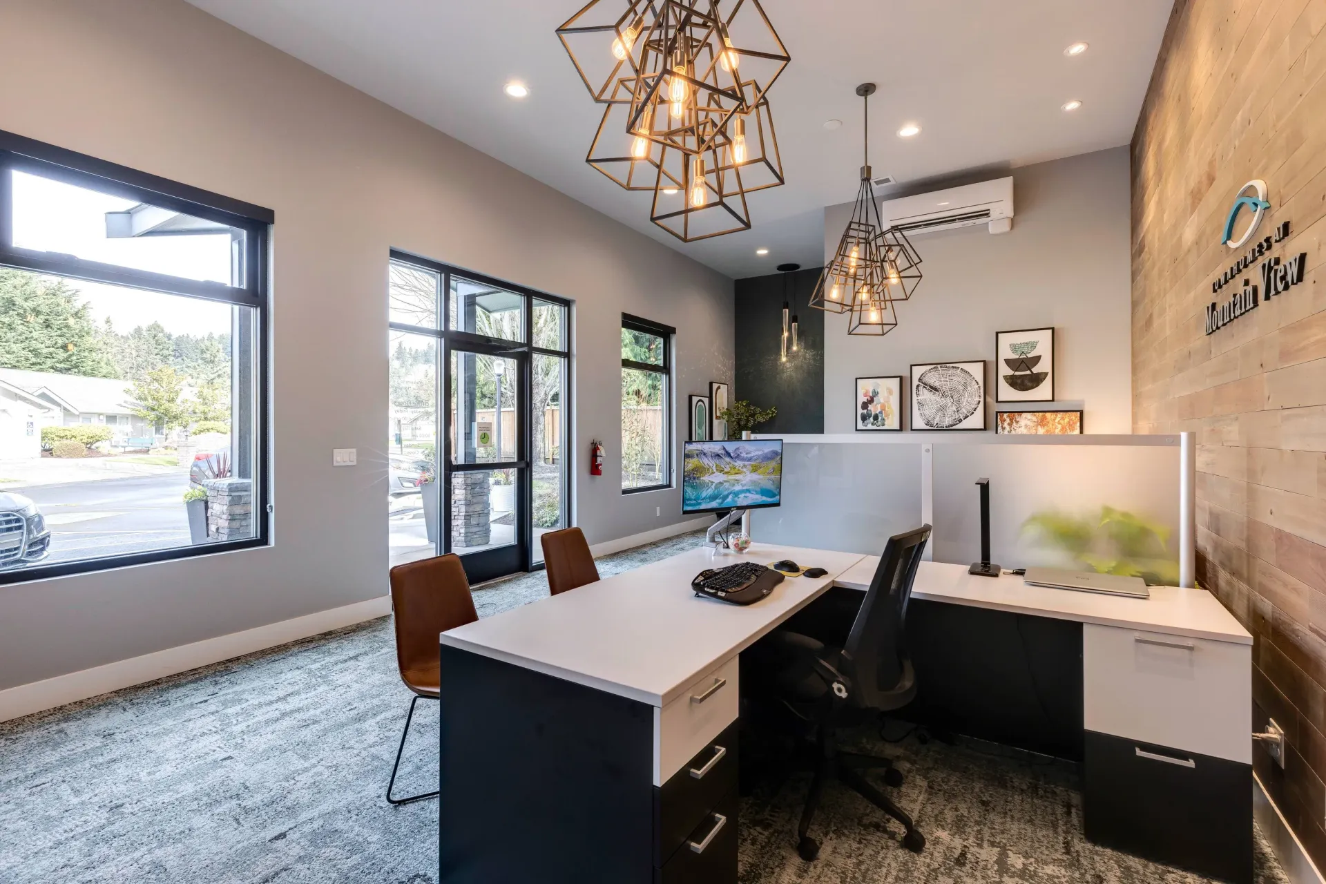 Modern leasing office reception with desk, glass divider, and pendant lights.
