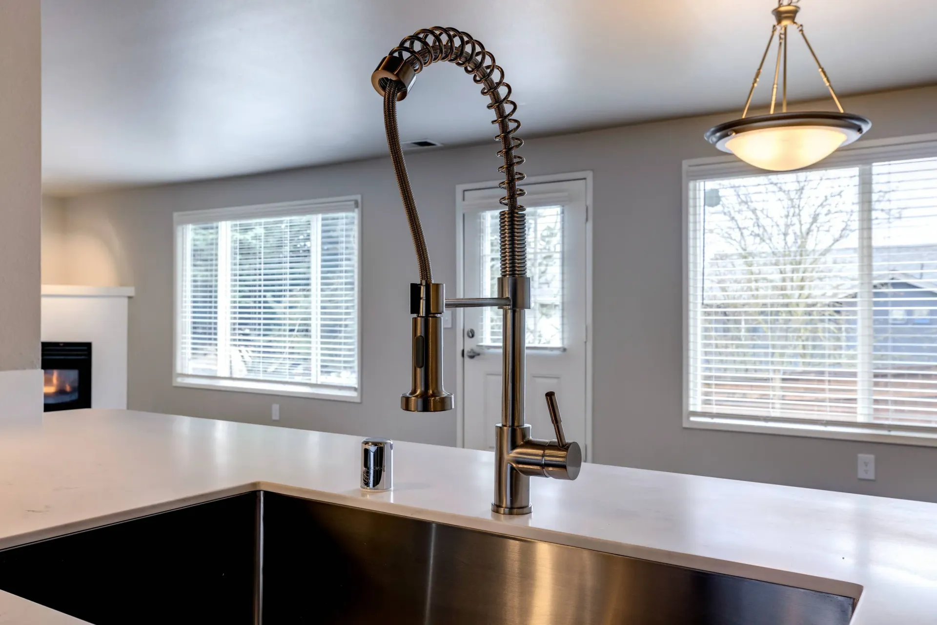Modern stainless steel pull-down kitchen faucet over a white countertop.