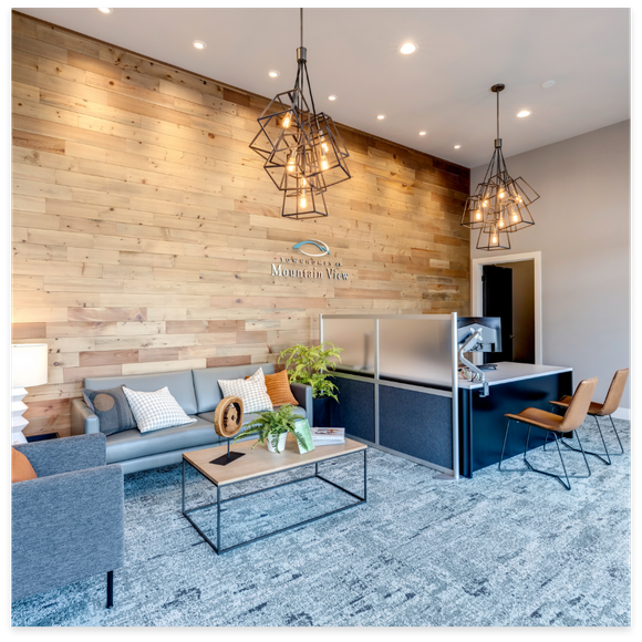 Reception area with wood-paneled wall, modern furniture, geometric light fixtures, and a reception desk.