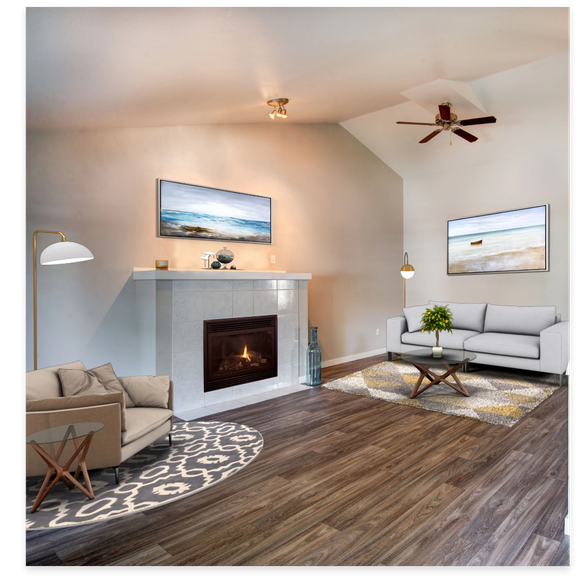 Living room with fireplace, seating, art, hardwood floors, and neutral colors.
