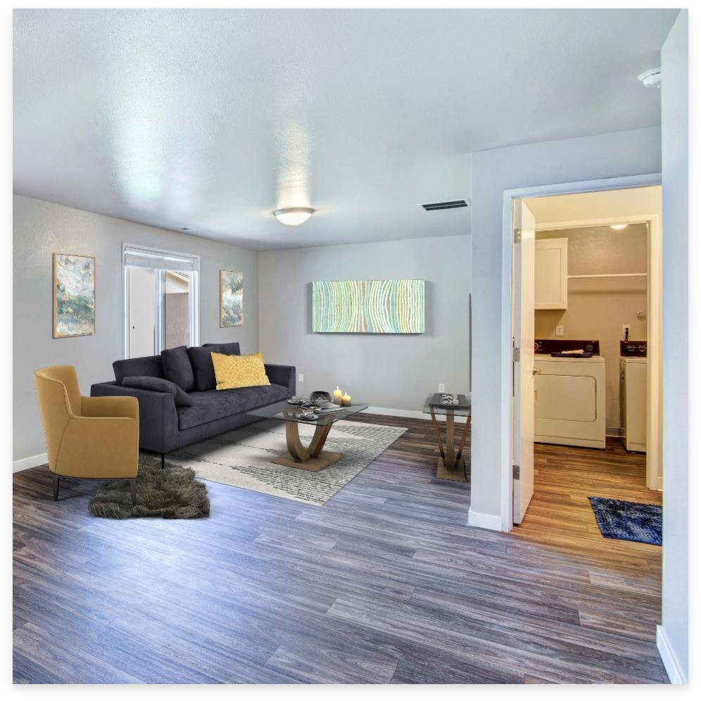 Living room with gray couch, mustard chair, wood floor, and laundry room visible.