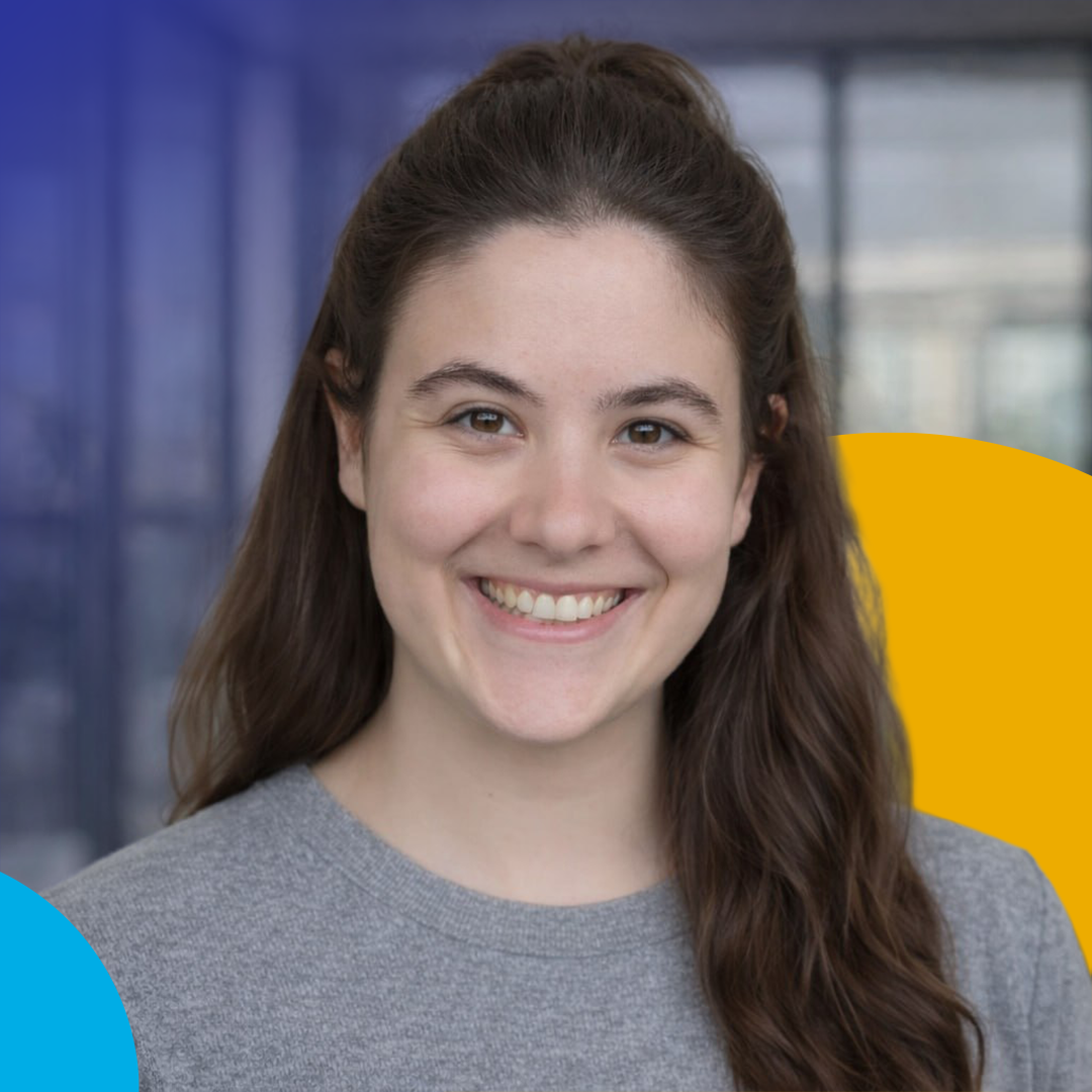 Blonde woman in white shirt smiling with arms crossed, holding glasses against a blue/yellow background.