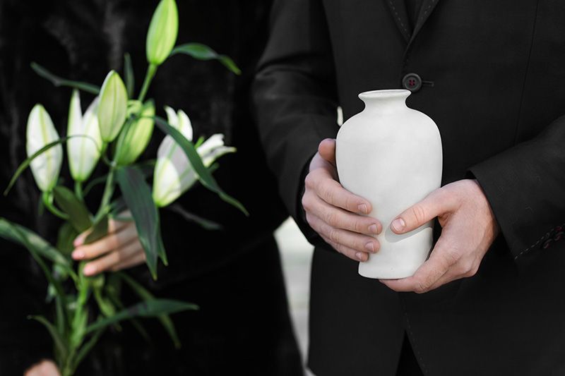 Cremation Services. Person holding white urn