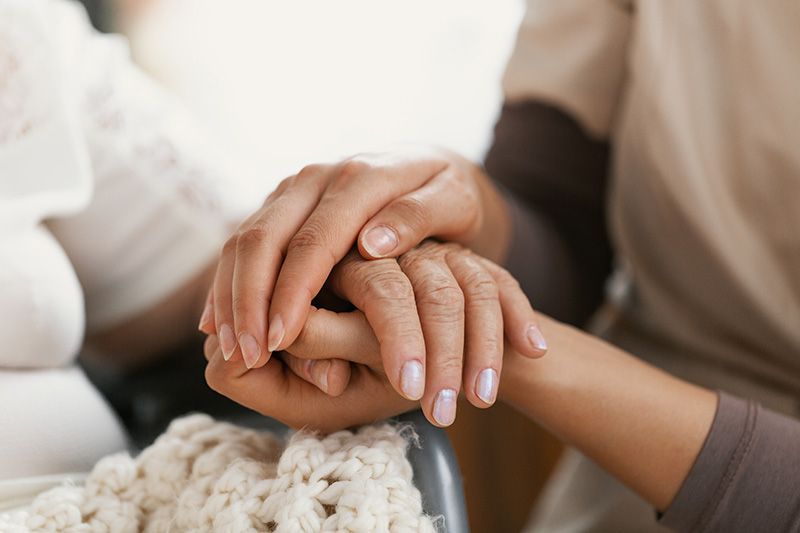 Grief Support.  Two people hands holding. One Showing support for loved one.