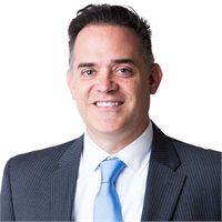 Man in a suit smiles at the camera, light blue tie.