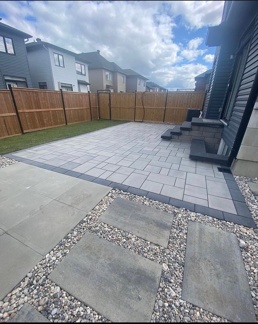 a patio with a wooden fence and steps in front of a house .