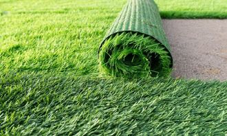 a roll of artificial grass is sitting on top of a lush green lawn .