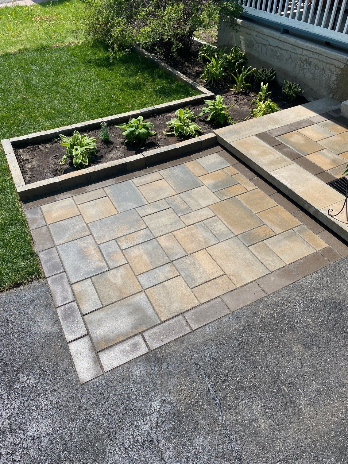 a patio with a planter in the middle of it and a lawn in the background