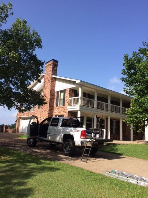 A white truck is parked in front of a large house.