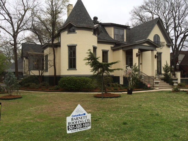 A house with a sign in front of it that says barney roofing co.