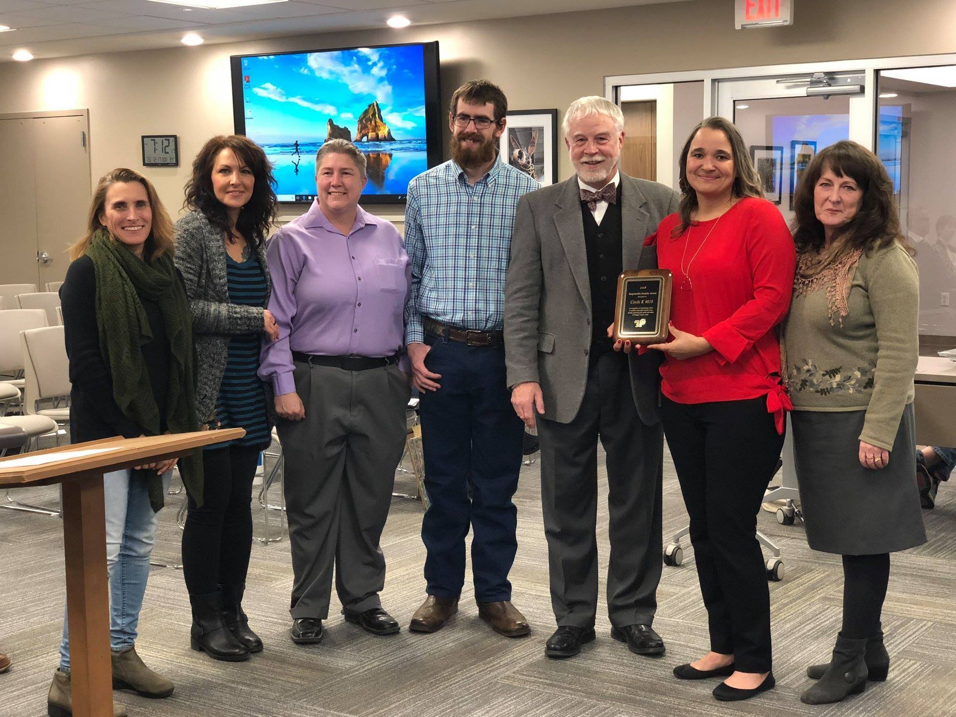 A group of people posing for a picture with a man holding a plaque